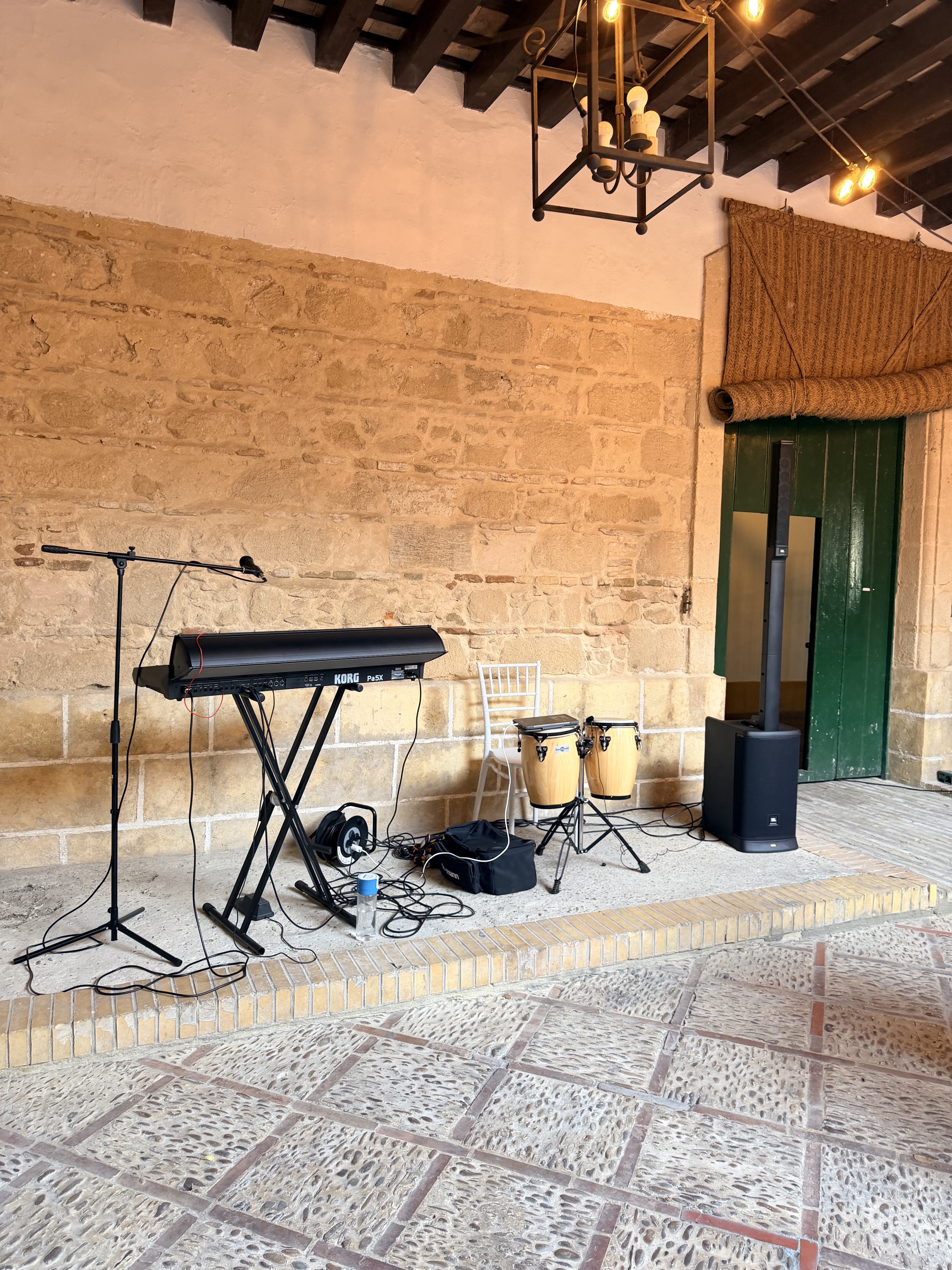 Montaje de LATITUDE con teclado, micrófono, percusión y altavoz en un espacio para eventos